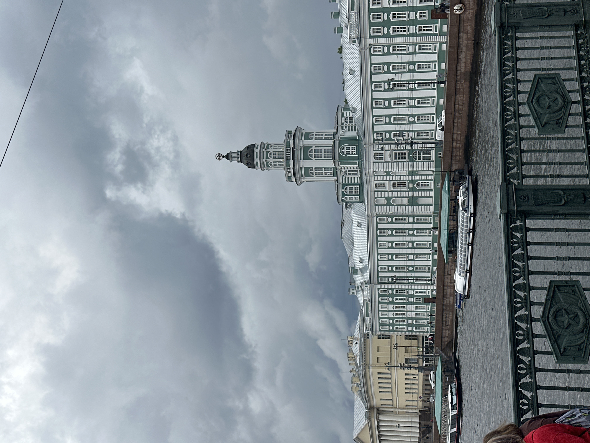 Green and white riverside building under overcast urban skies