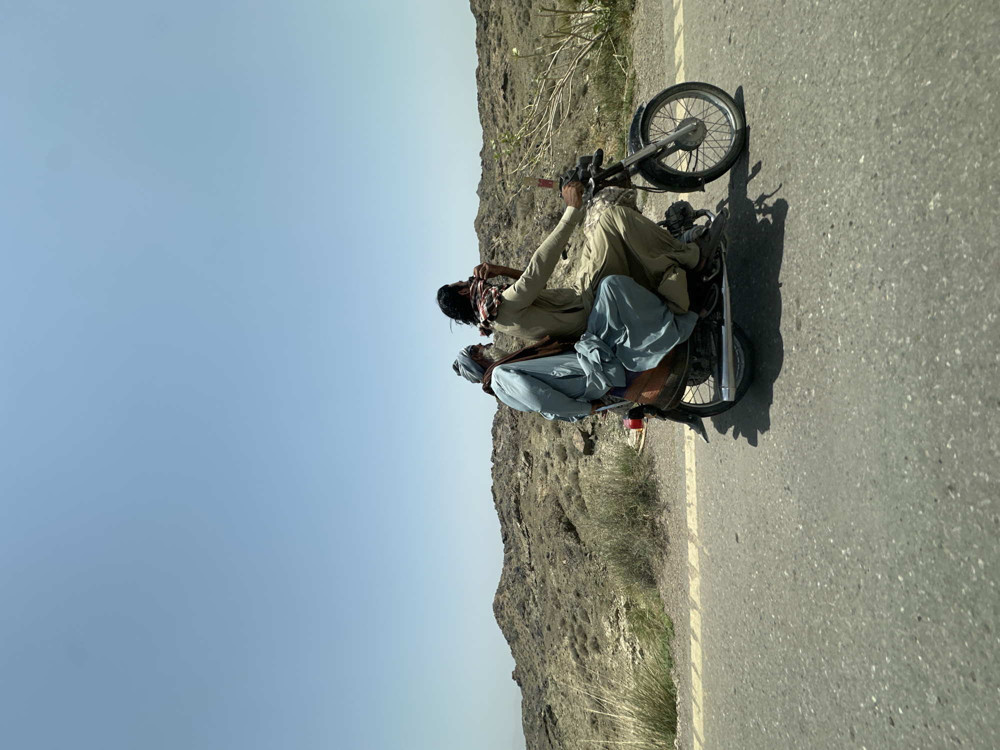 Motorcycle duo in traditional dress on a Pakistani road