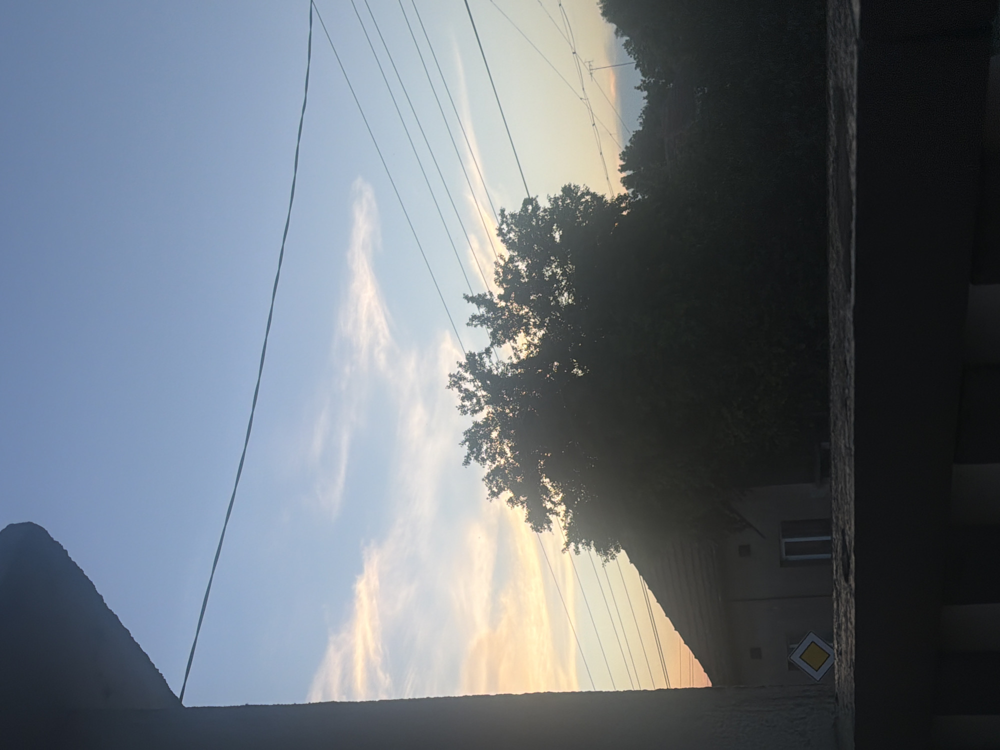 Person documents sunset balcony moment with flowers and flip-flops