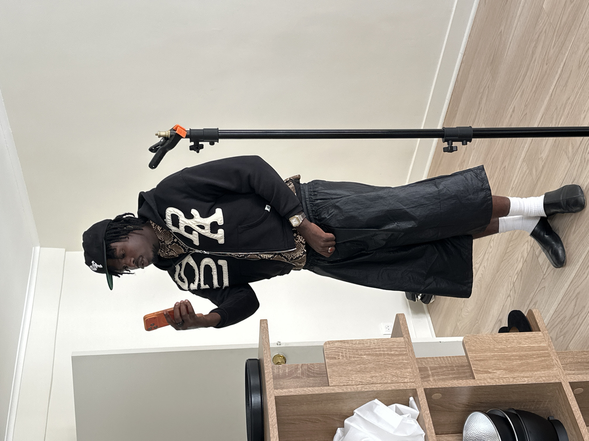 Man in black attire uses orange phone indoors in Paris