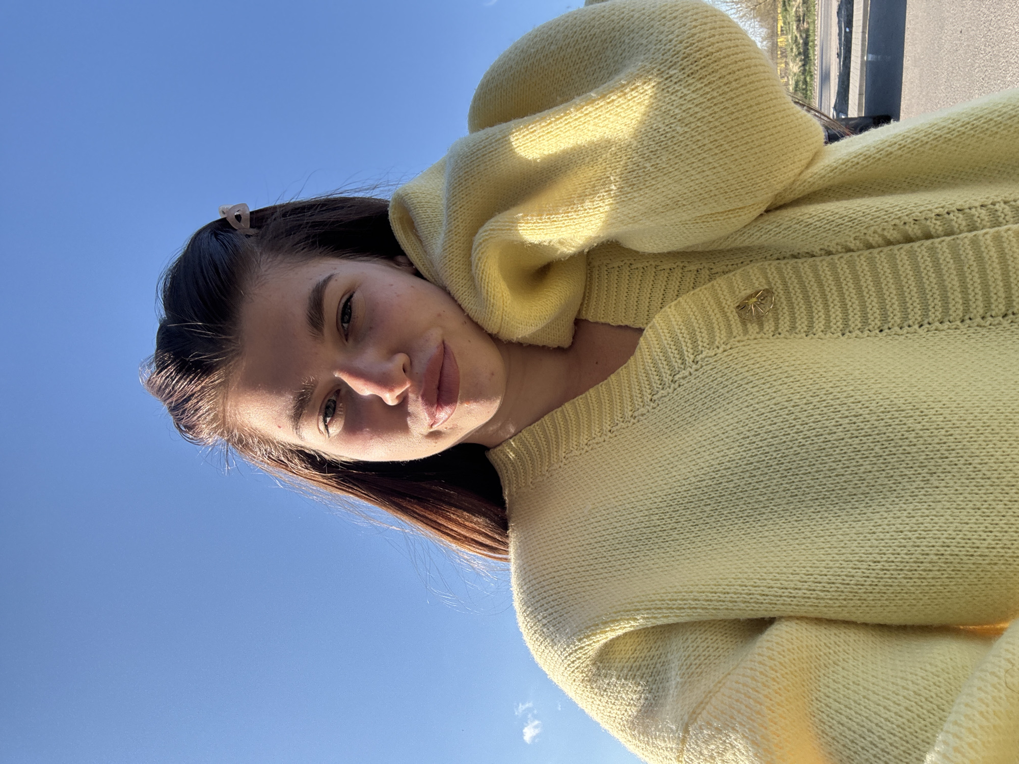 Woman in yellow sweater photographed against blue sky in Russia
