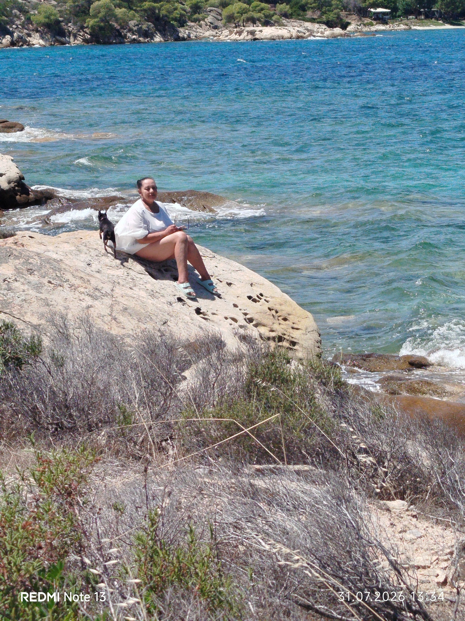 Sunny morning on the rocks in Sithonia with a small black dog
