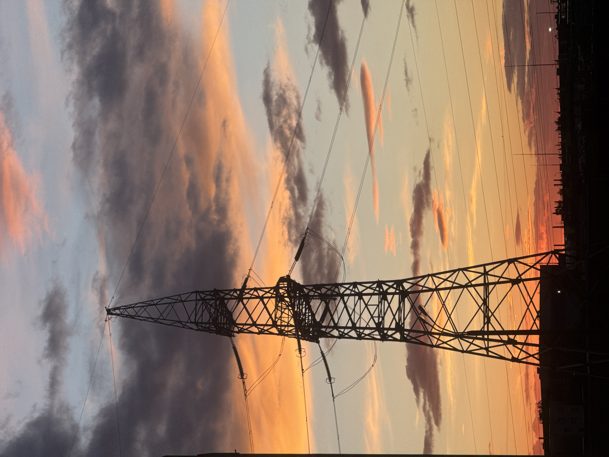 Evening sunset illuminates Minsk power infrastructure, resident walks nearby