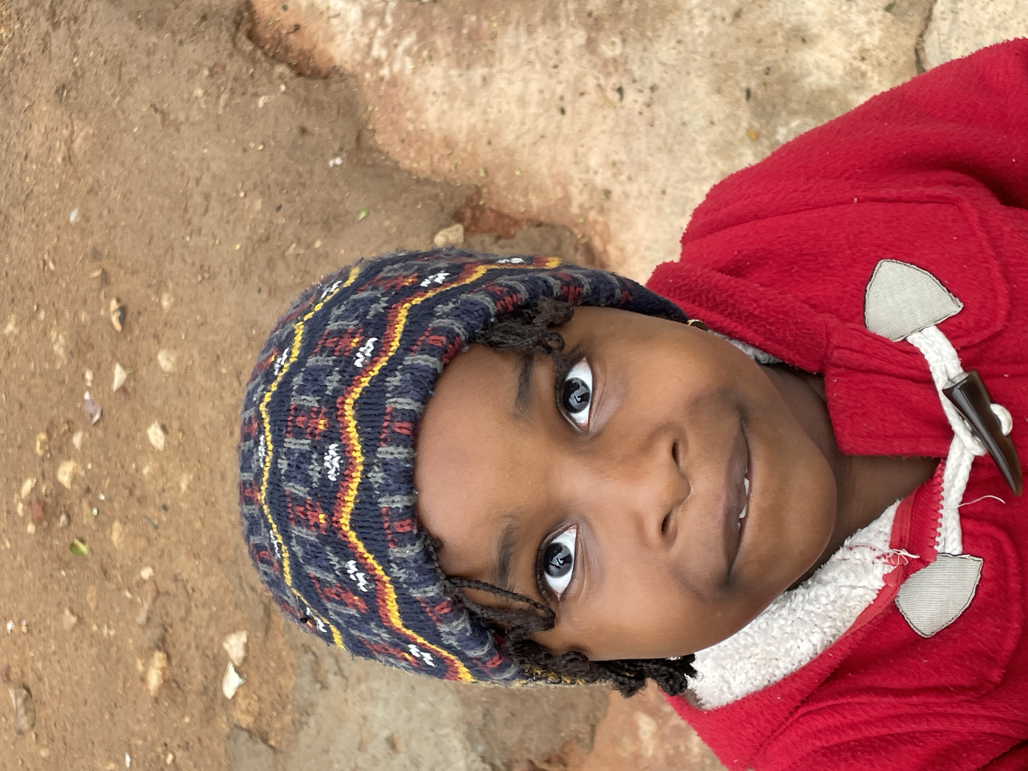 Child in red jacket photographed playing outdoors in Jos