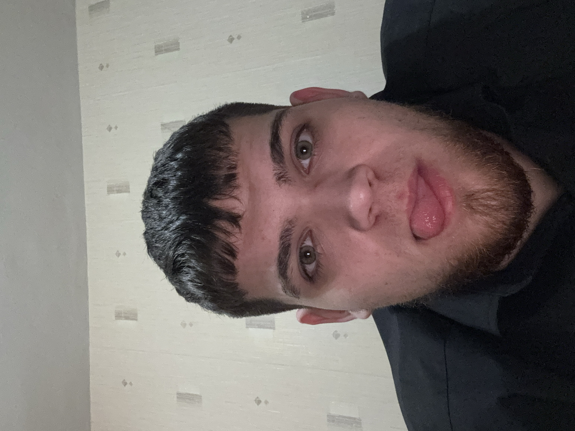 Man in black hoodie makes playful face indoors
