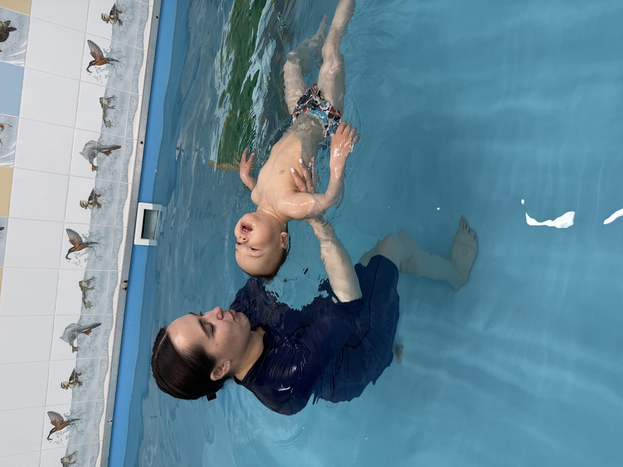 Woman holds child during swimming pool session