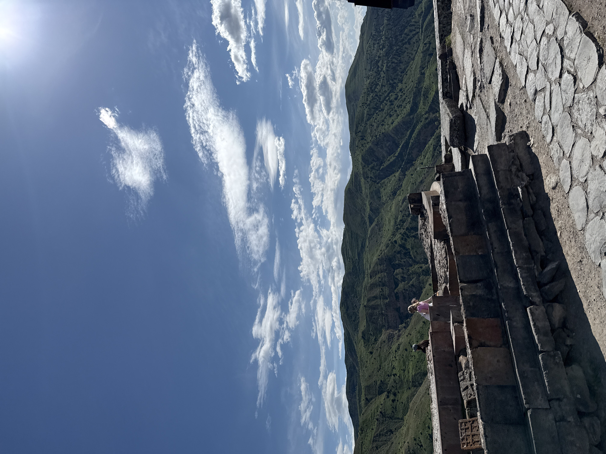 Tourist visits ancient Temple of Garni under partly cloudy skies