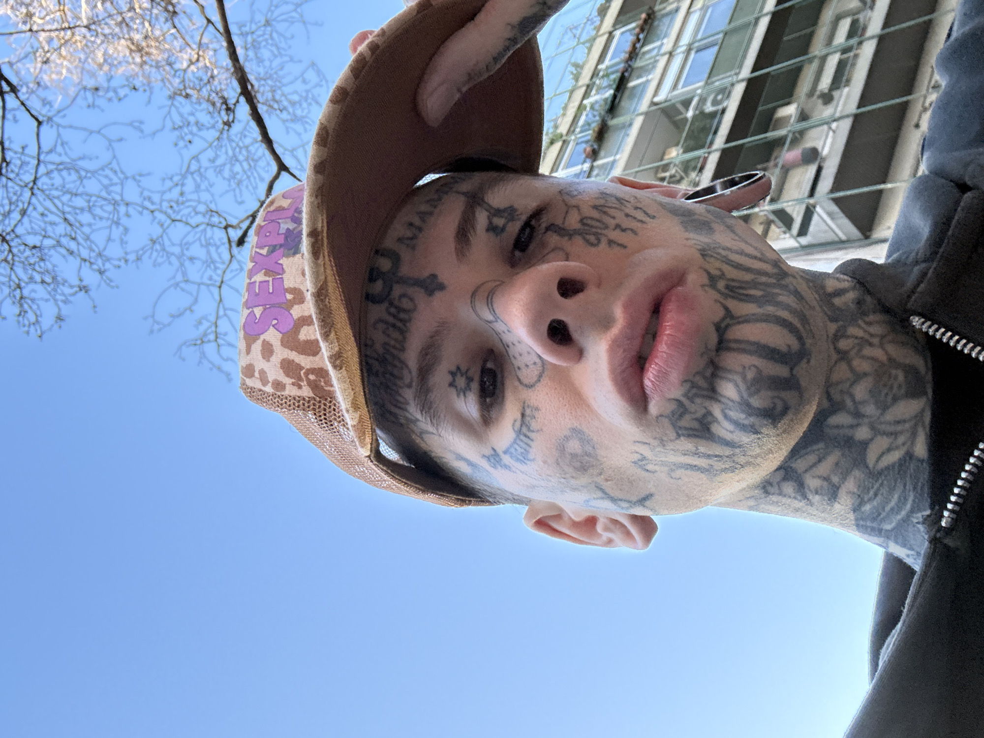 Tattooed individual spotted on Buenos Aires sidewalk wearing distinctive headwear