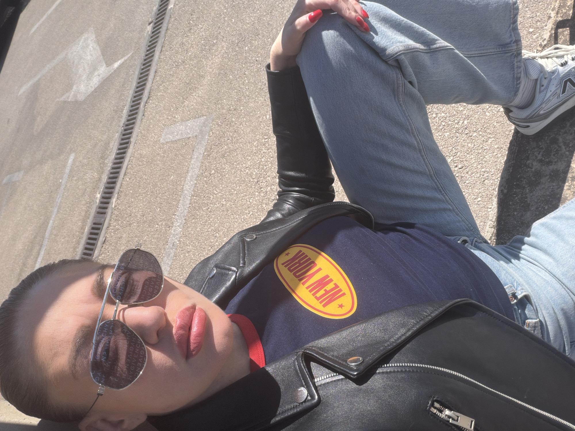 Person in New York shirt rests on pavement in Bar