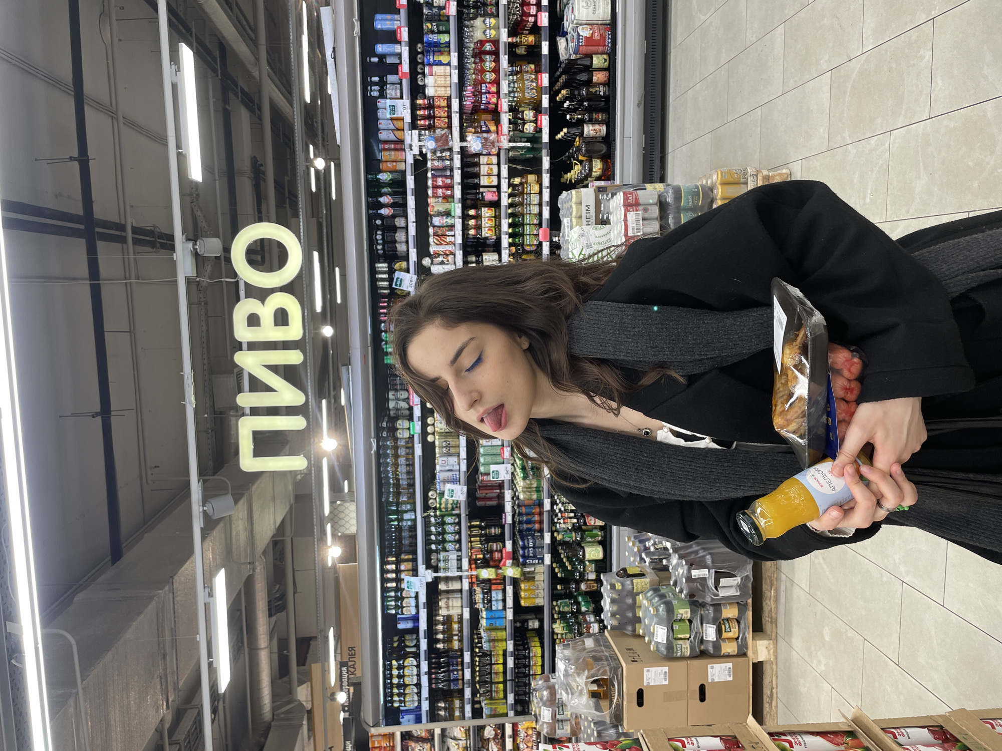 Woman shopping for orange juice in supermarket aisle