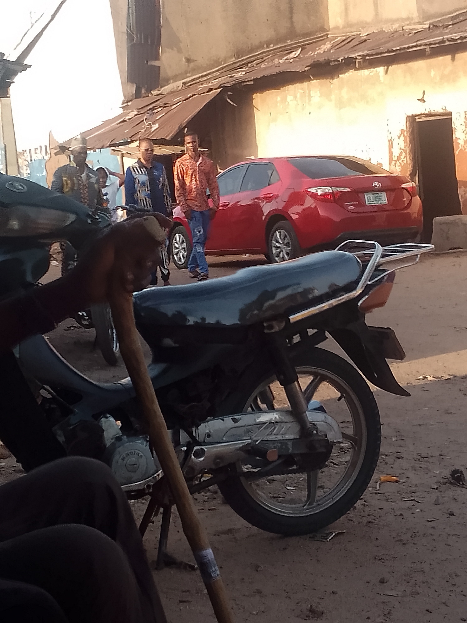 Urban street scene: parked motorcycle, pedestrian carrying items