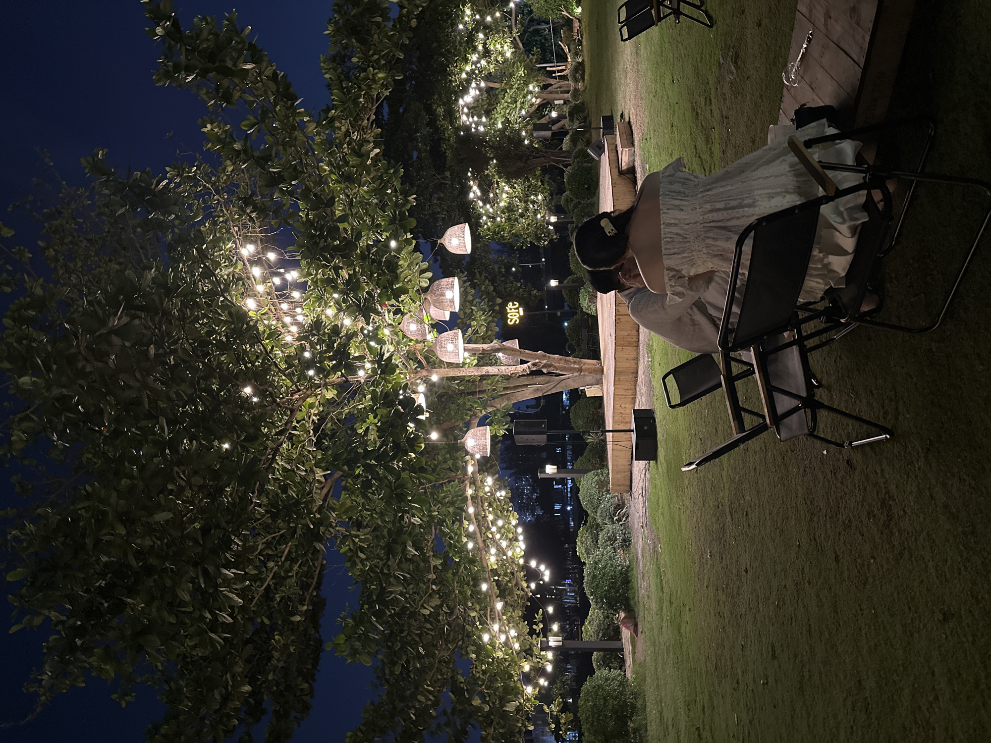 Woman dines at illuminated outdoor cafe in Ho Chi Minh City