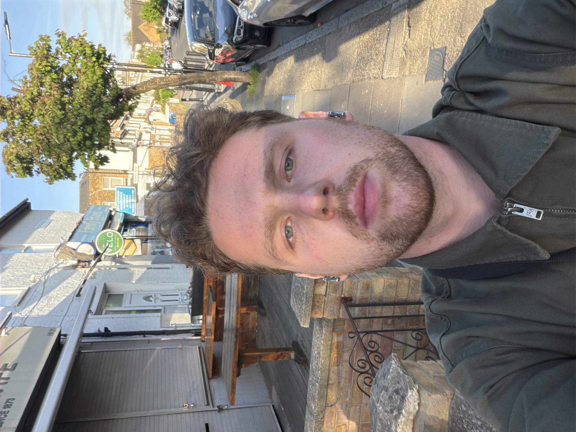 Individual takes selfie on sunlit London street Thursday evening