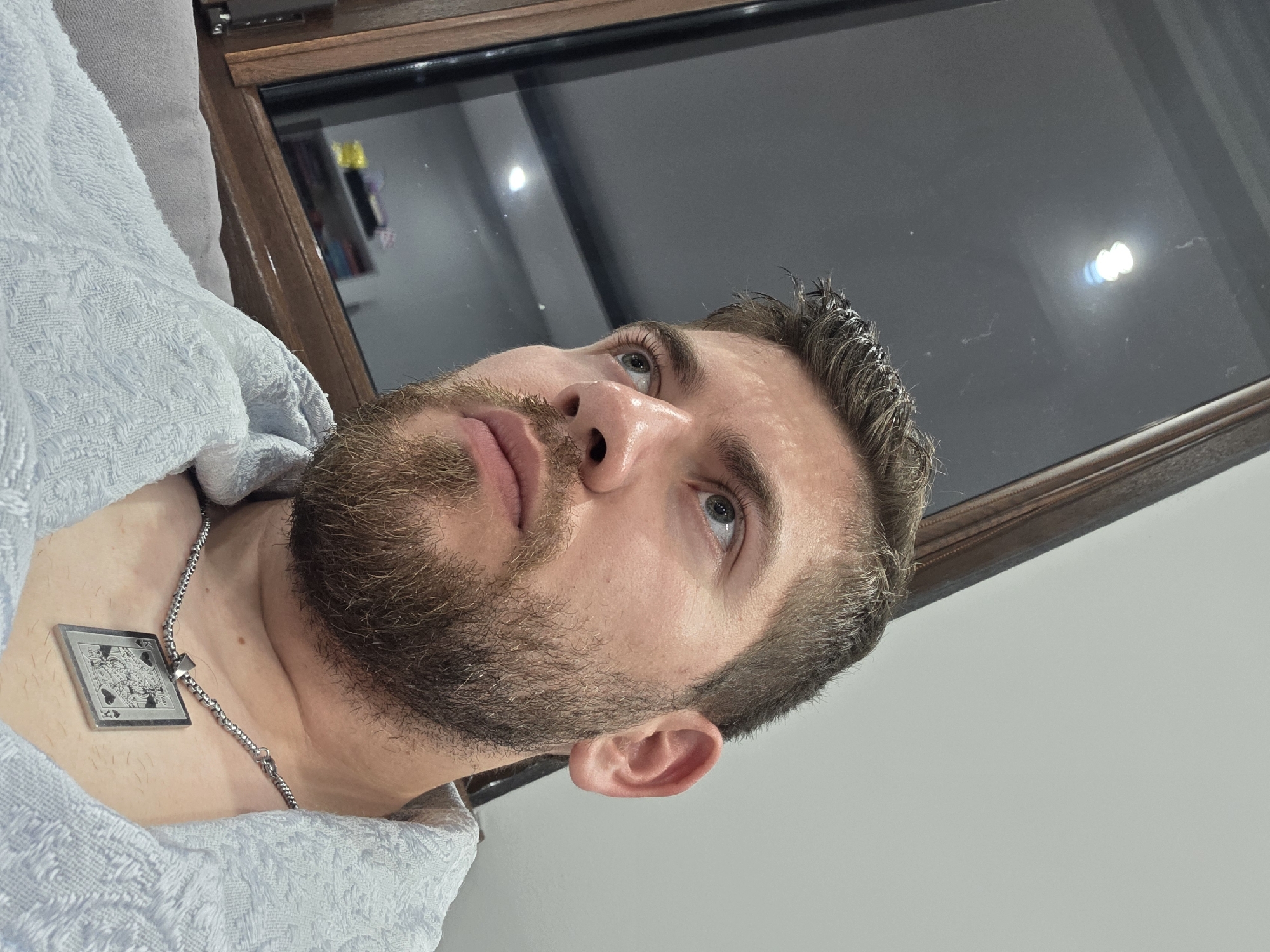 Man photographed in bathrobe with card pendant necklace indoors