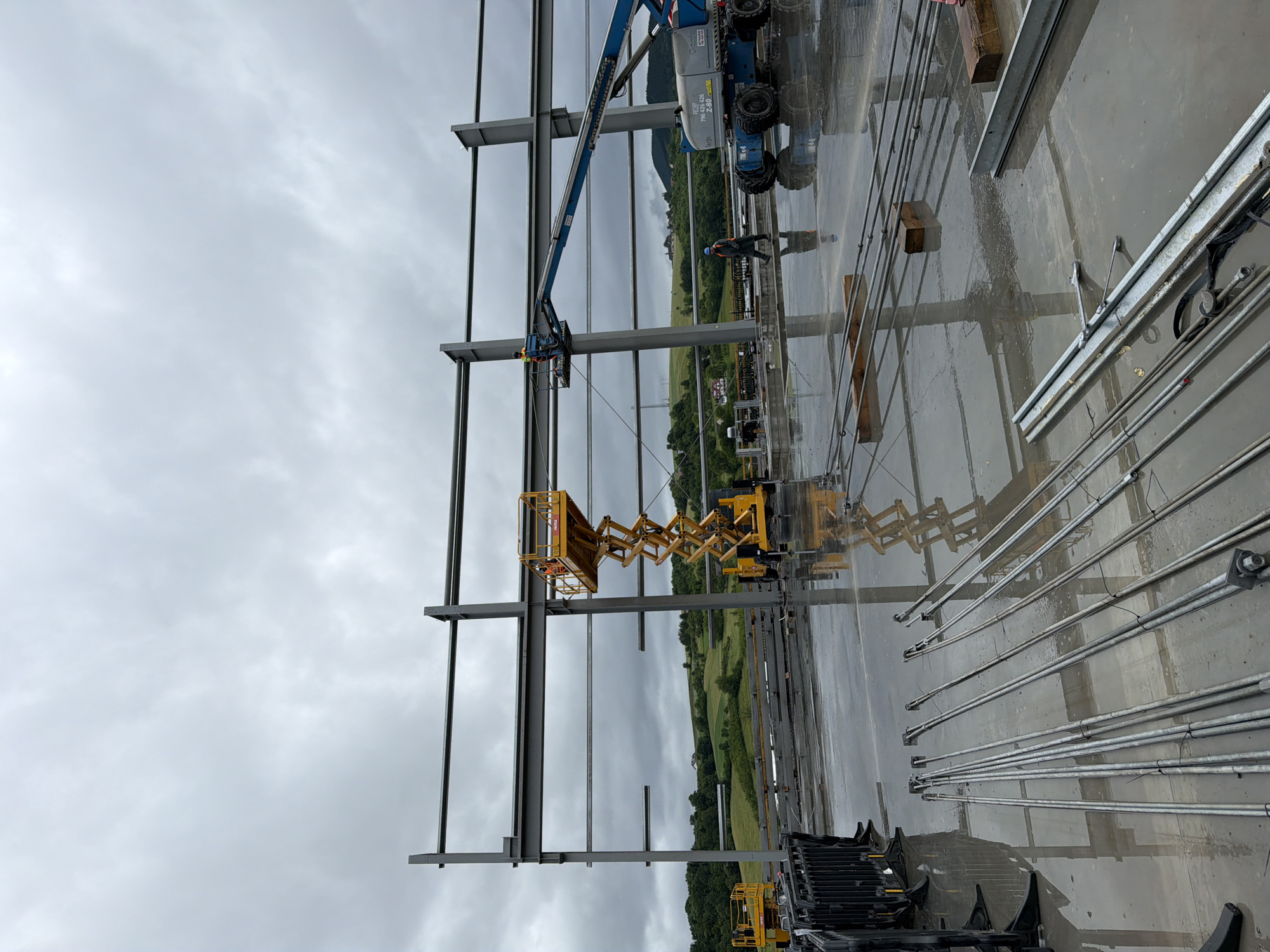 Construction crew works industrial site in cloudy Janowice morning
