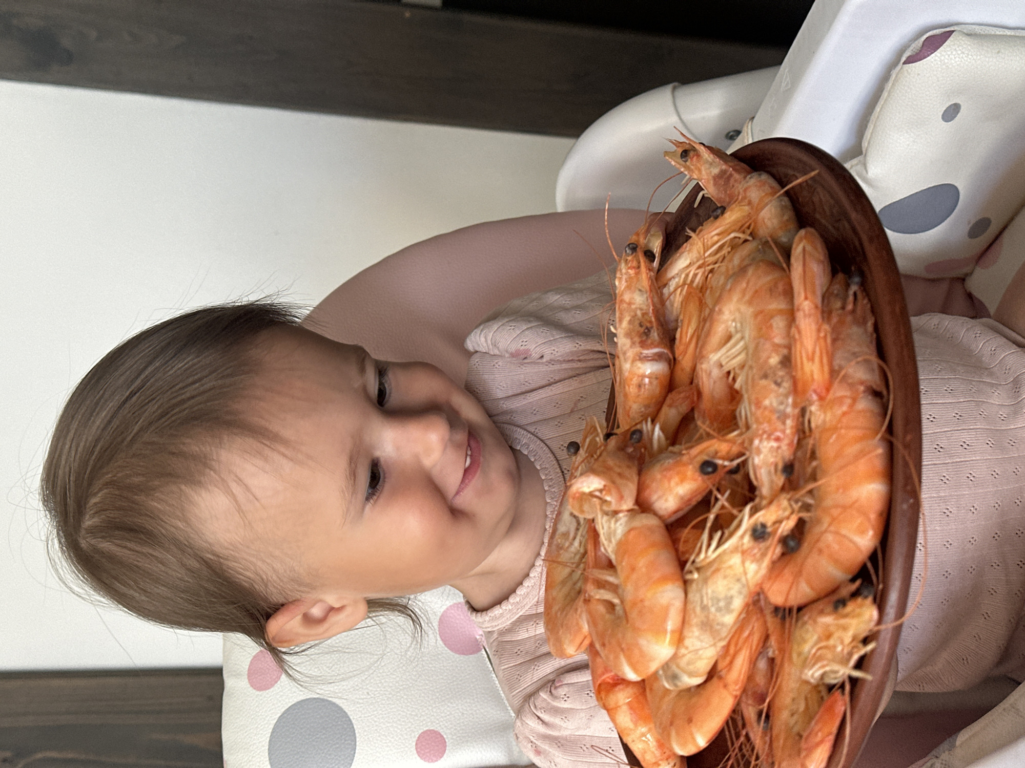 Child enjoys shrimp meal in high chair in Wisła