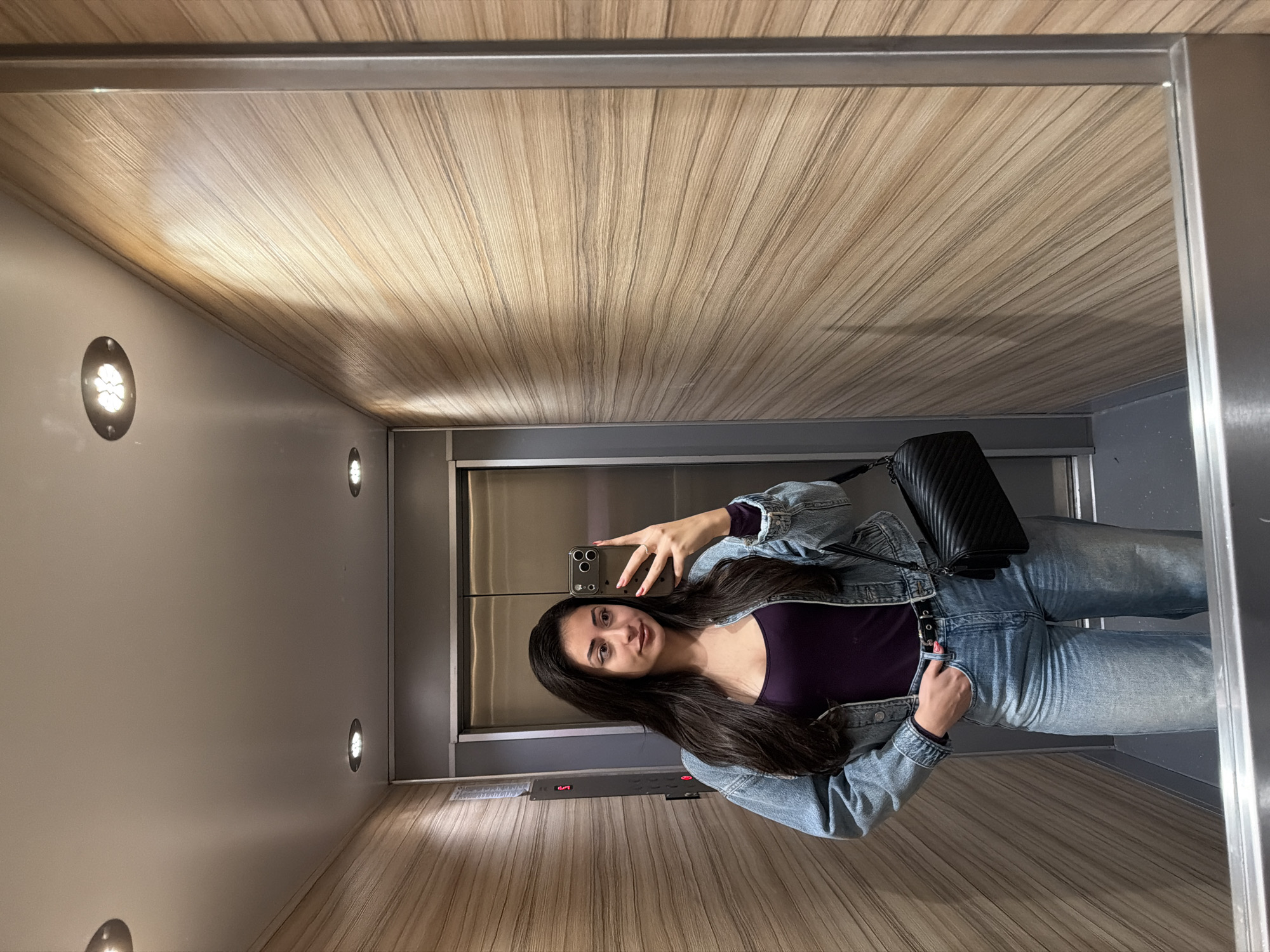 Woman takes selfie in wooden-paneled elevator in Sofia