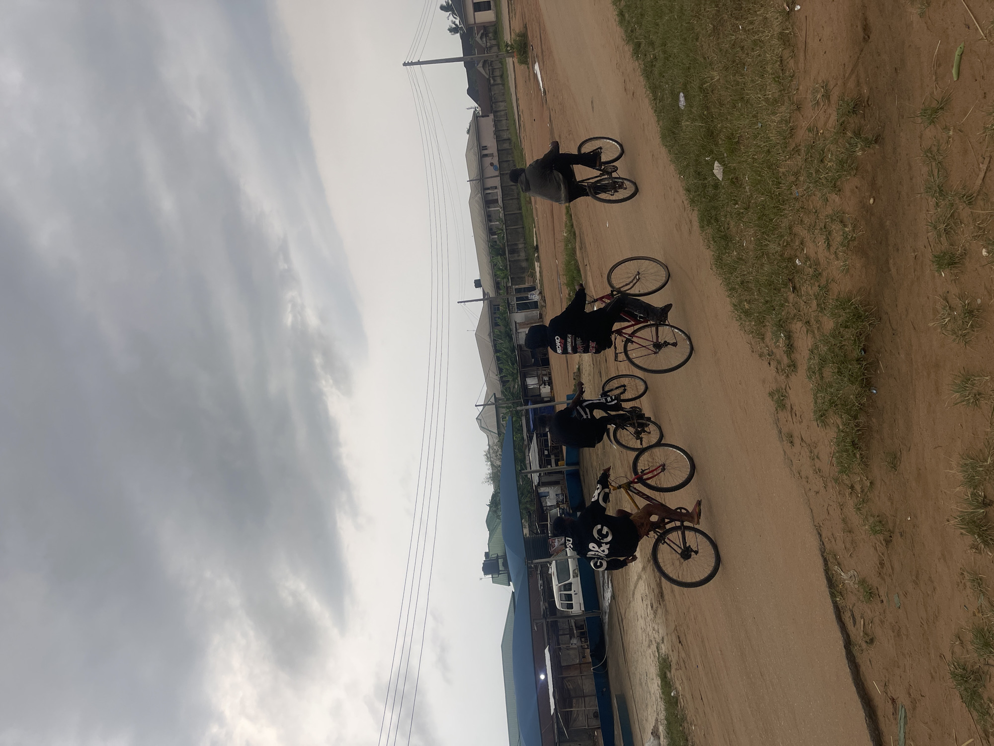 Four cyclists ride dirt road in Abraka, Nigeria
