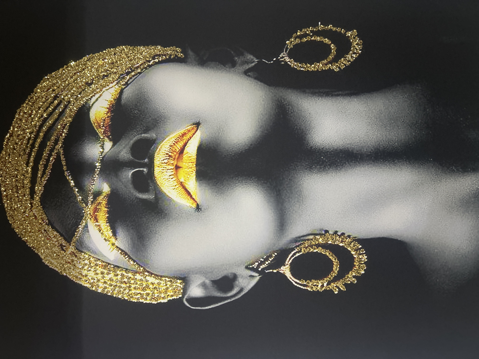 Portrait artwork with gold accents photographed on white wall