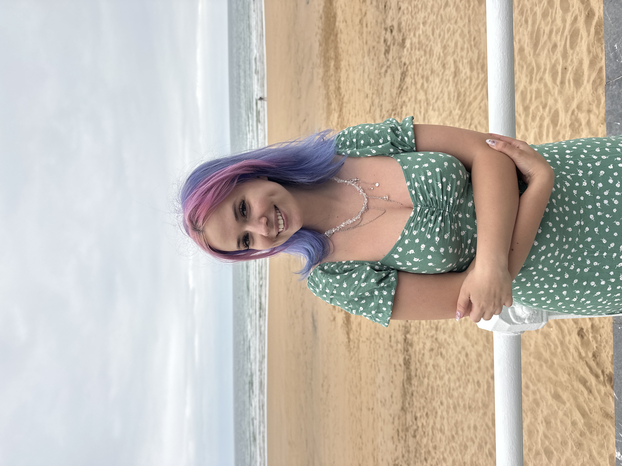 Woman poses at Gijón beach promenade under overcast evening sky