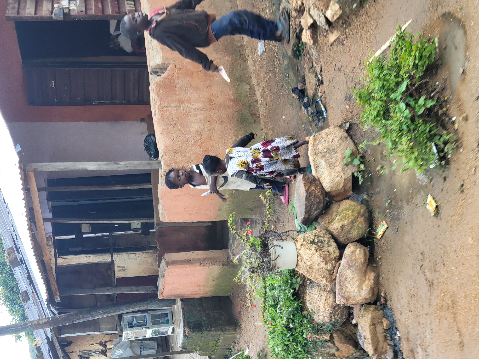 Everyday street life along a muddy Jos neighborhood strip