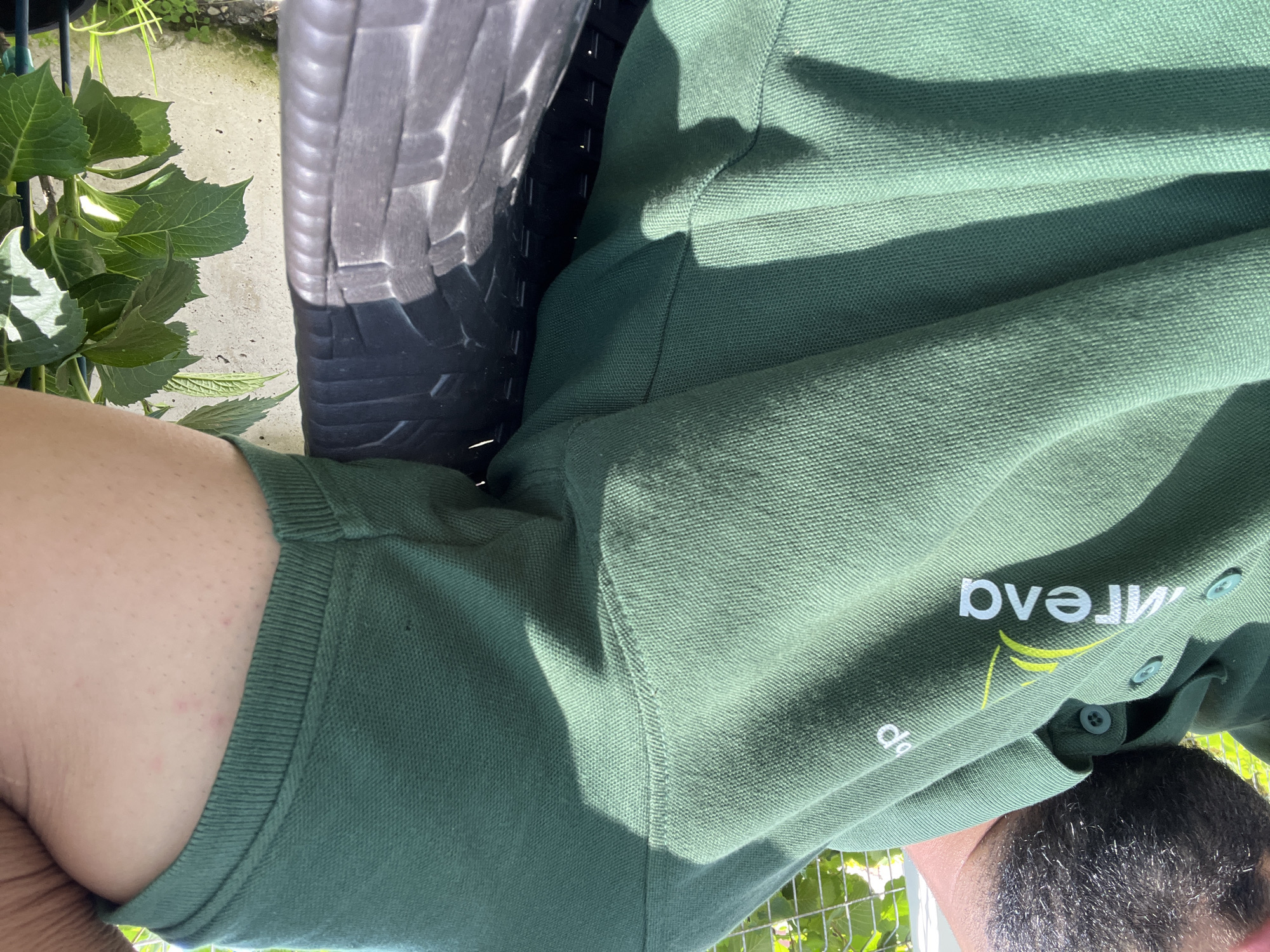 Close-up details: a branded polo shirt and a blooming begonia