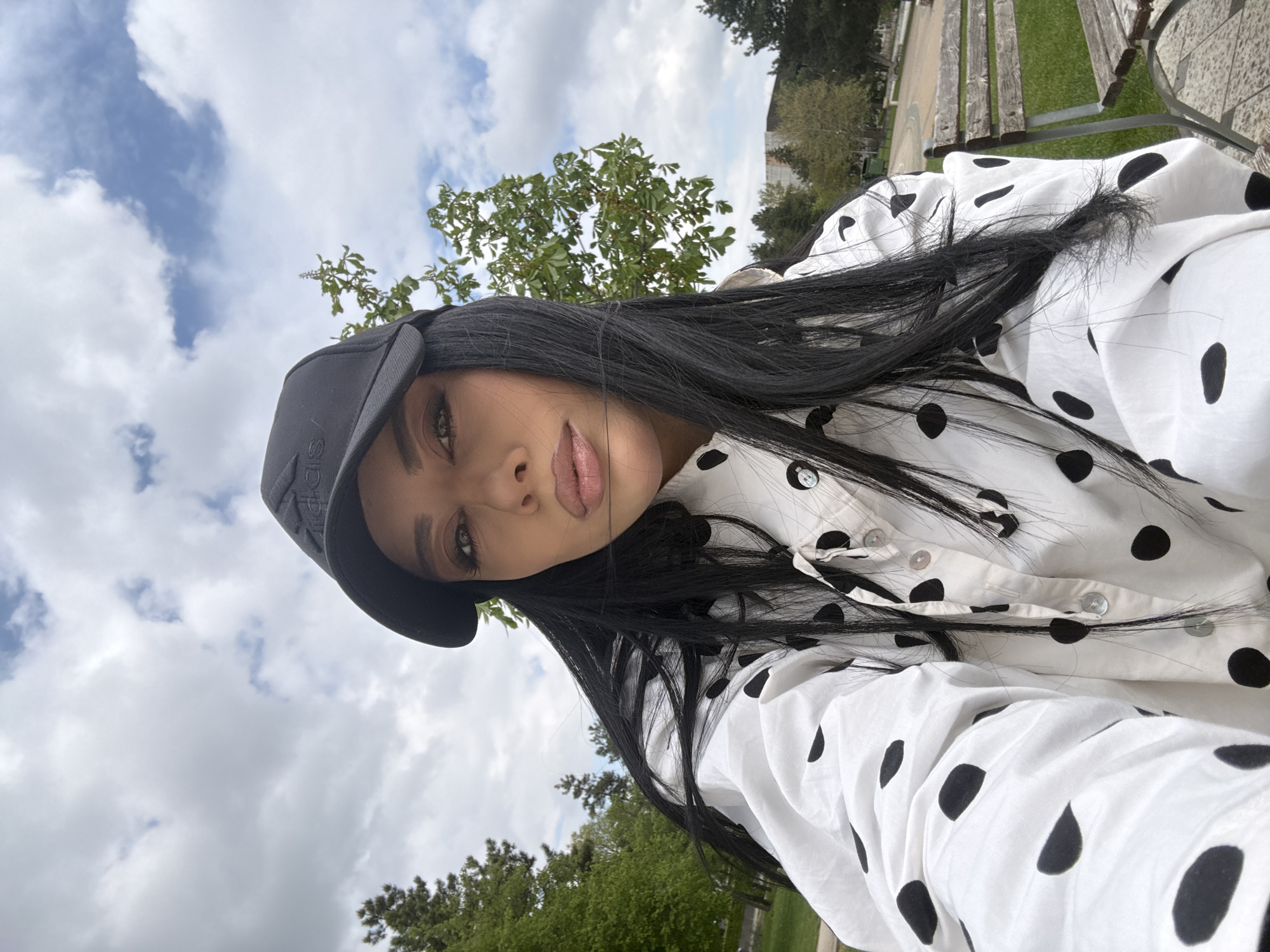 Woman in polka dot shirt photographed outdoors under cloudy skies