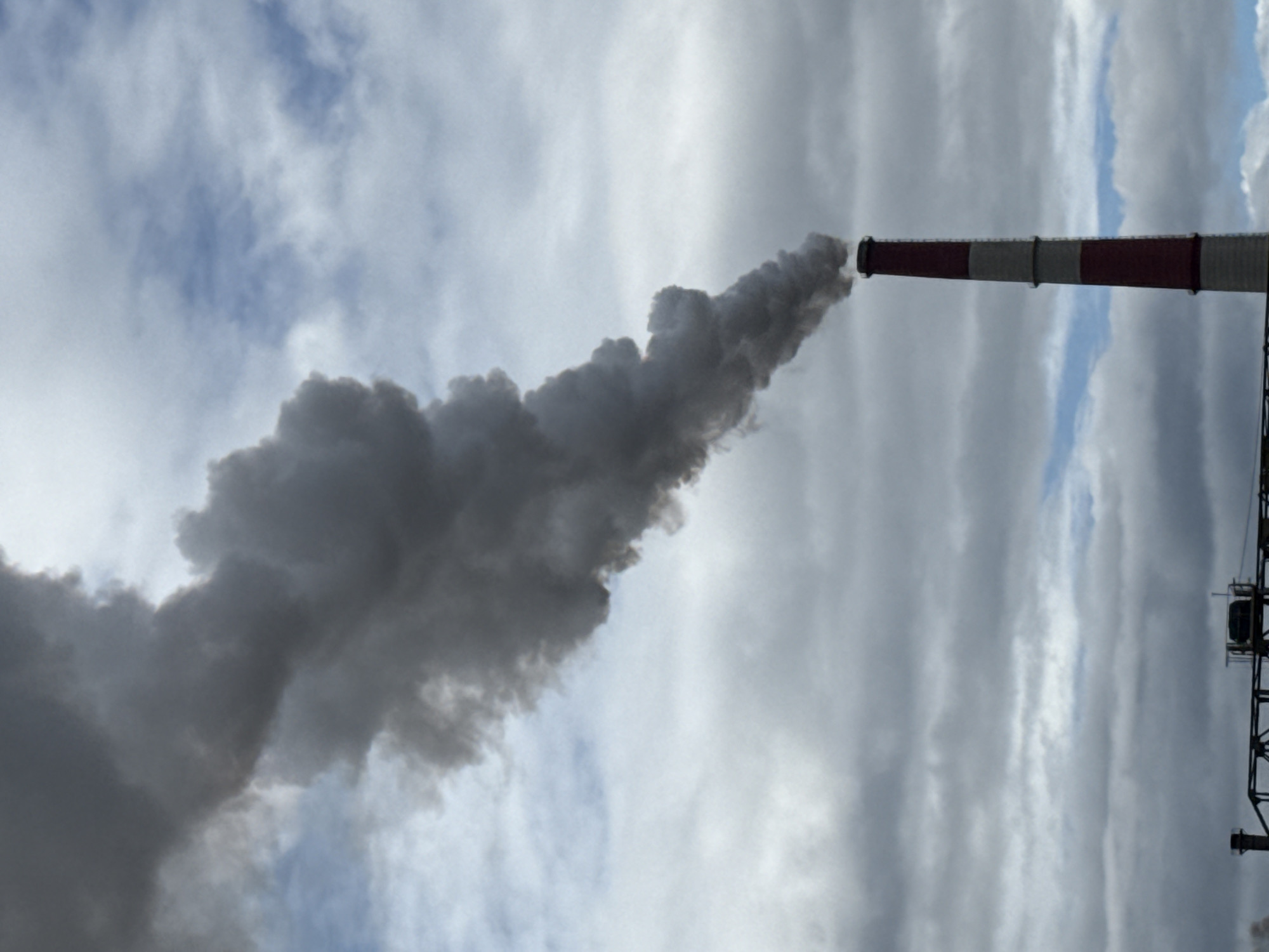 Heavy smoke pours from a striped industrial stack in Norilsk