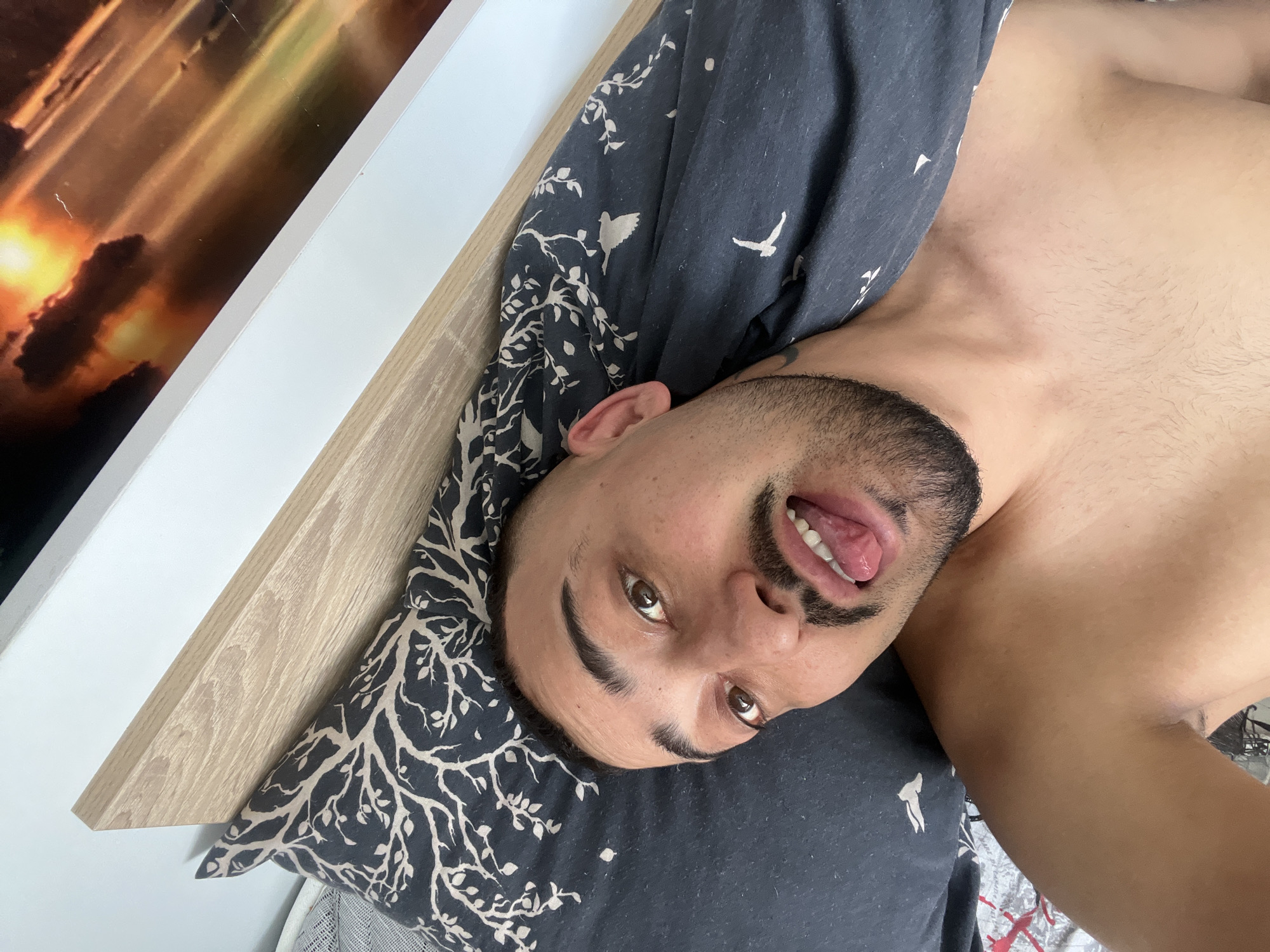 Man makes playful tongue gesture while lying in bed