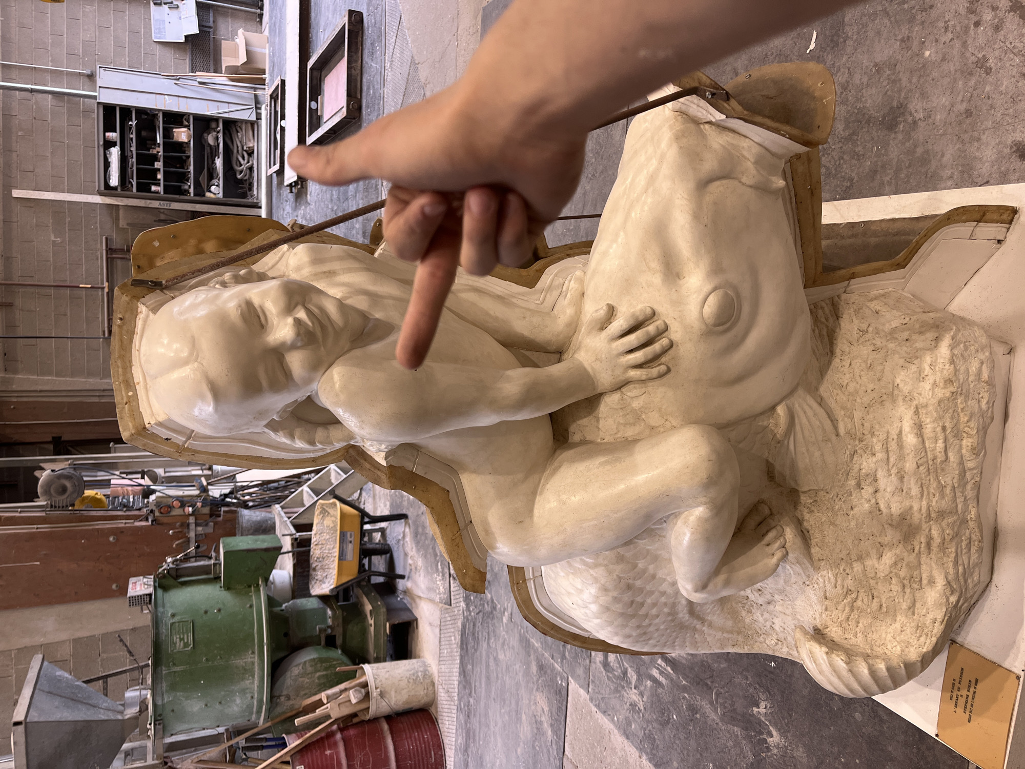 Artist points to human-fish sculpture in French workshop