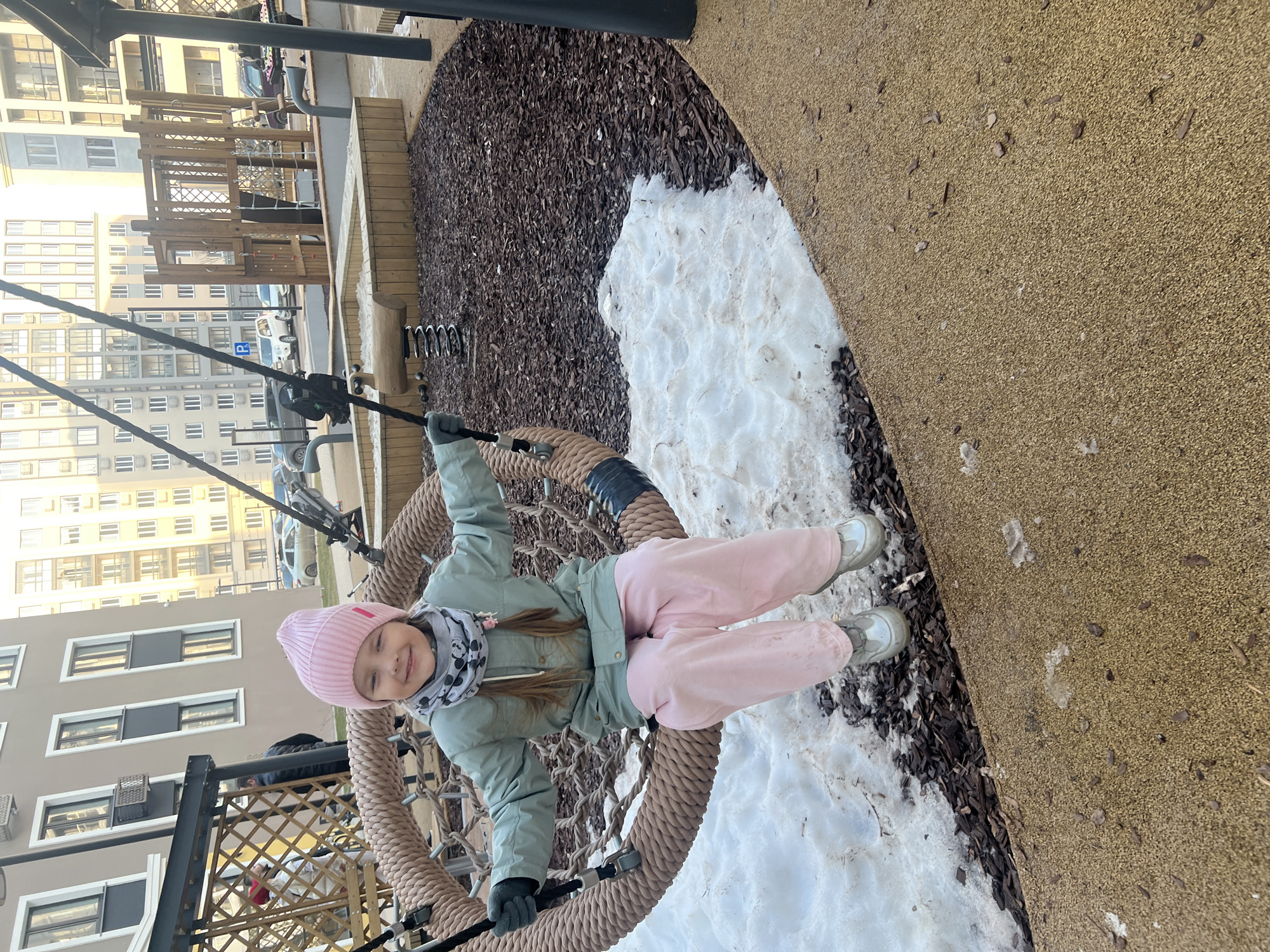 Girl enjoys playground swing in snowy Russian town
