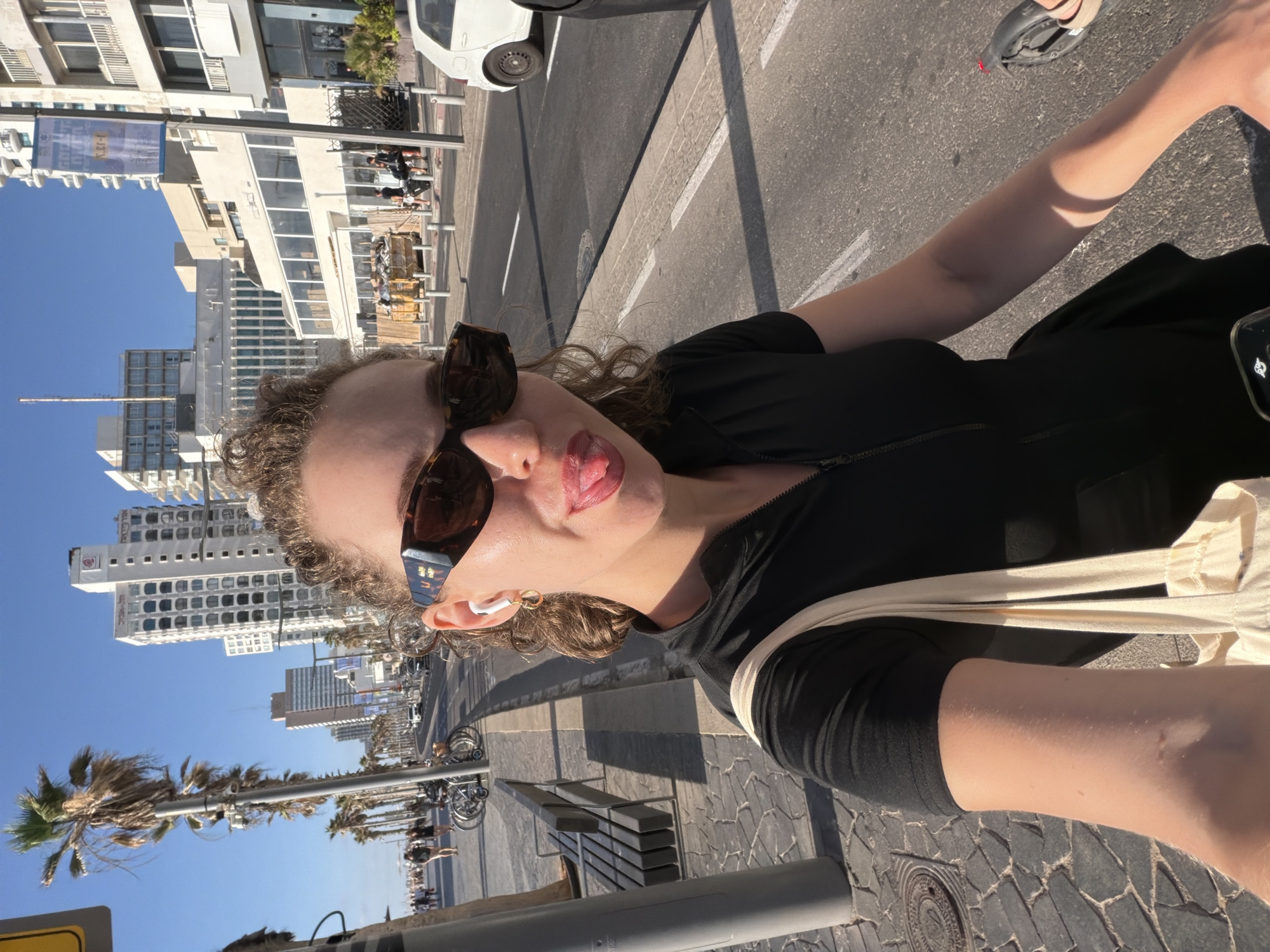 Outdoor selfie in Tel Aviv, sunglasses and earbuds on.