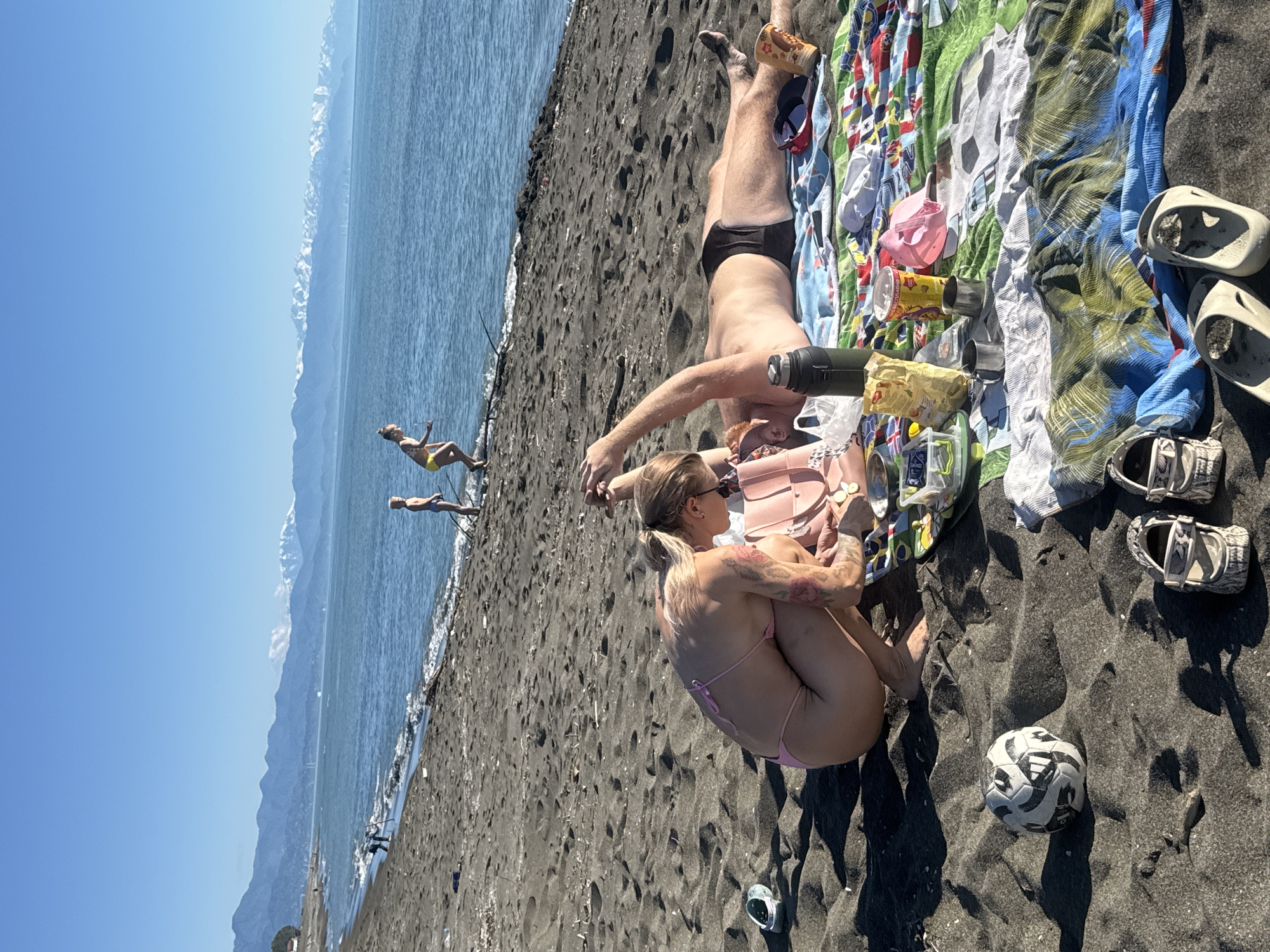 Beachgoers enjoy sunny afternoon at black sand beach