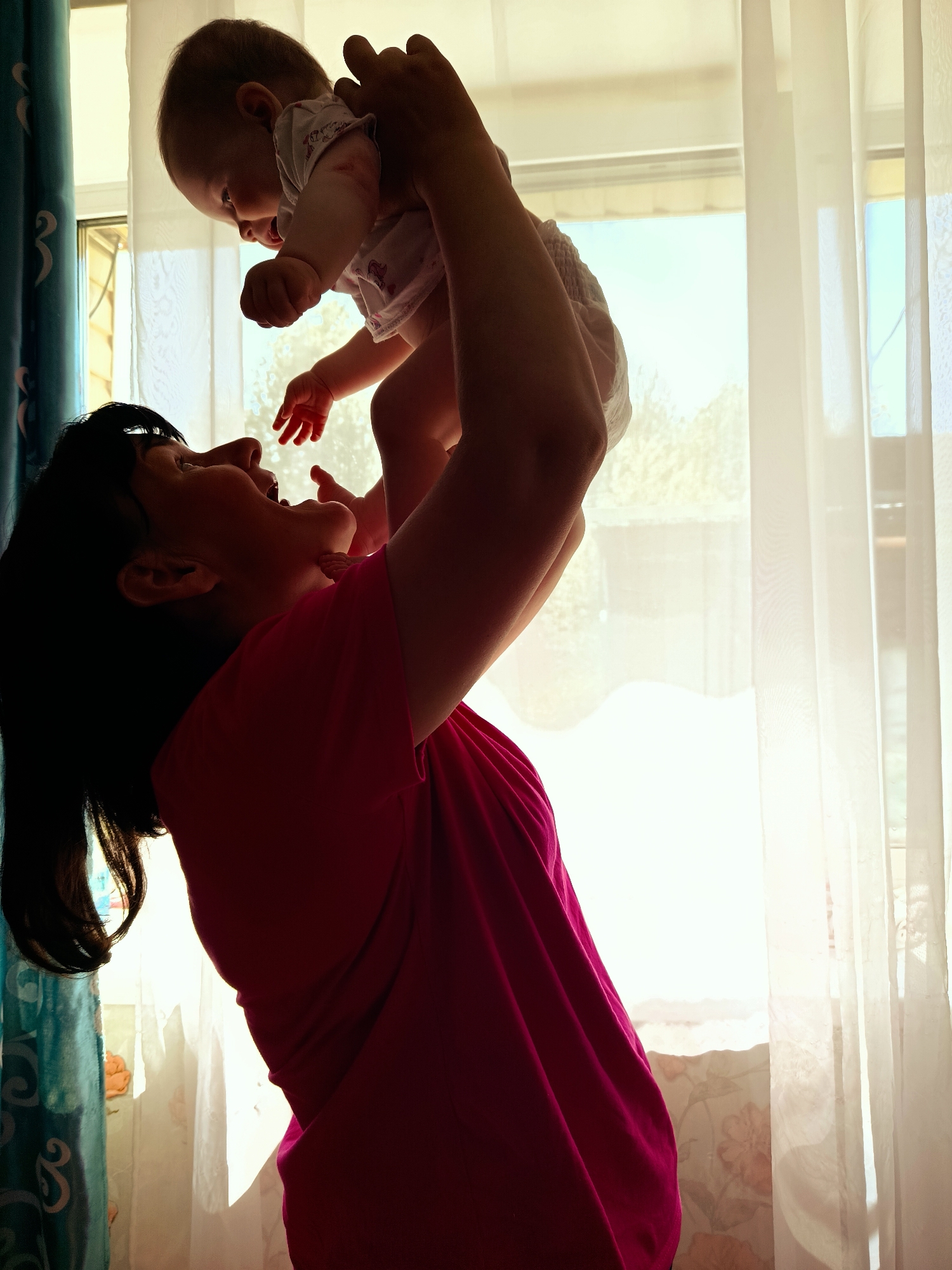 Mother holds baby near window in Foki, Russia