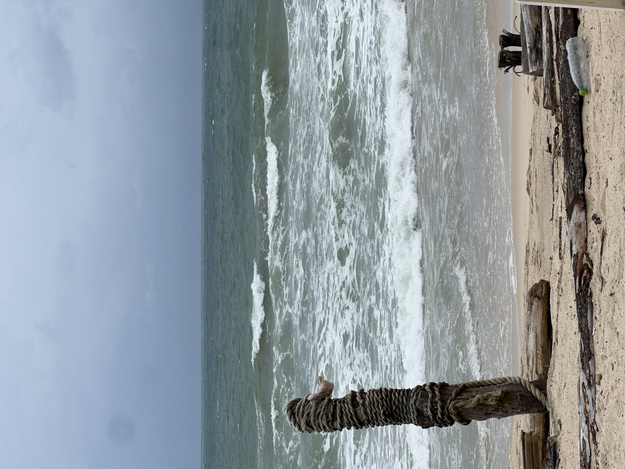 Red flag up, rough seas, empty chairs on a stormy beach.