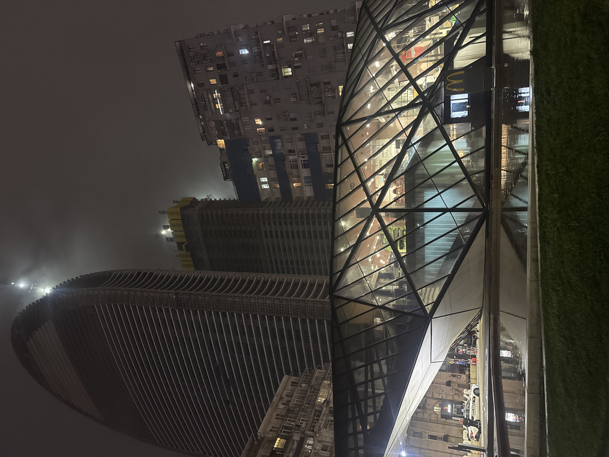 Nighttime urban scene centers on modern glass McDonald's restaurant