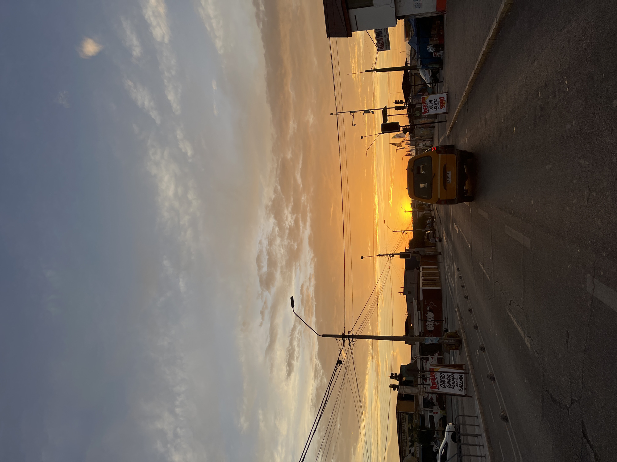 Yellow vehicle drives toward sunset on Arica street
