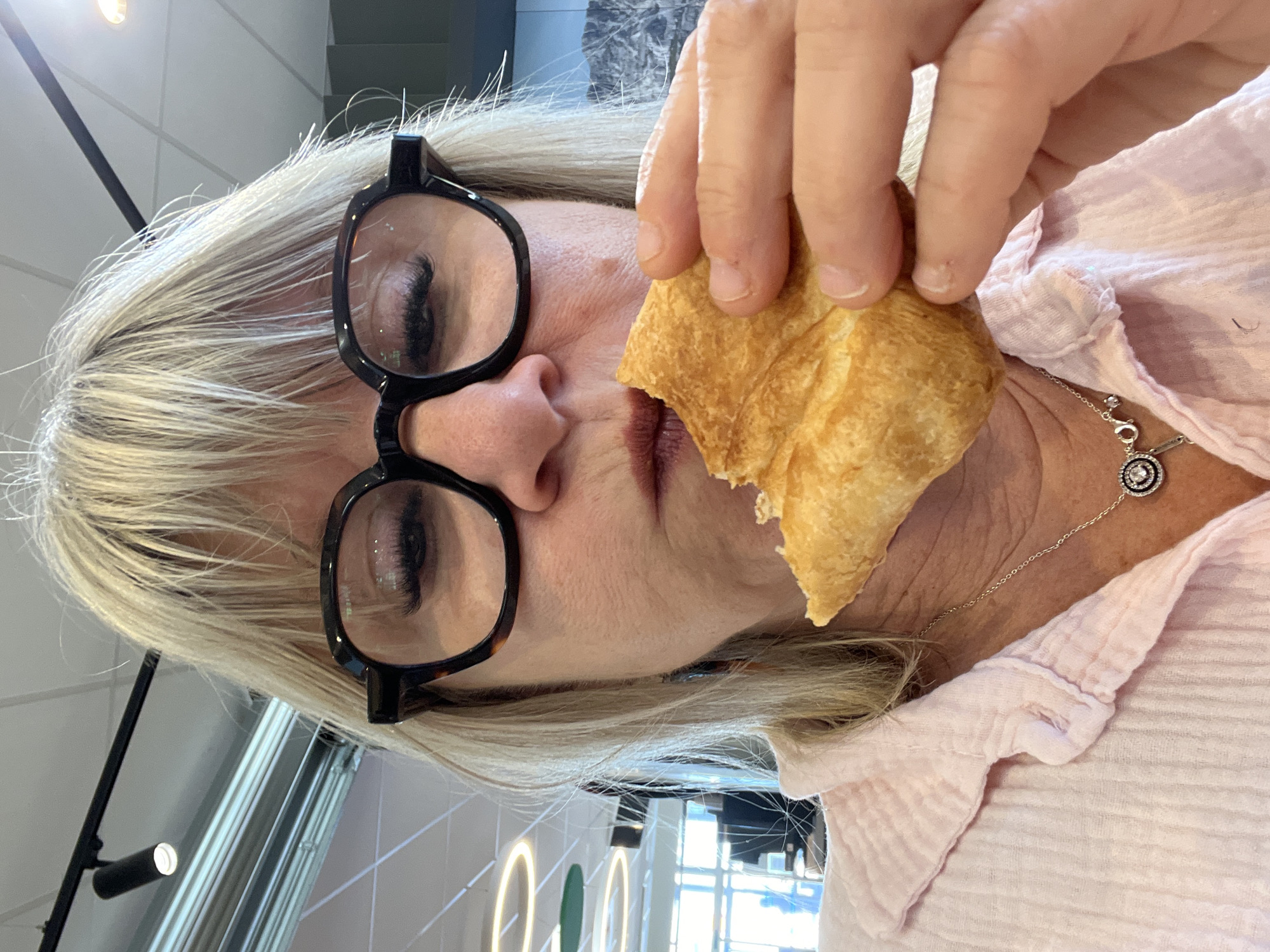 Woman enjoys breakfast croissant at Rousset cafe Friday morning
