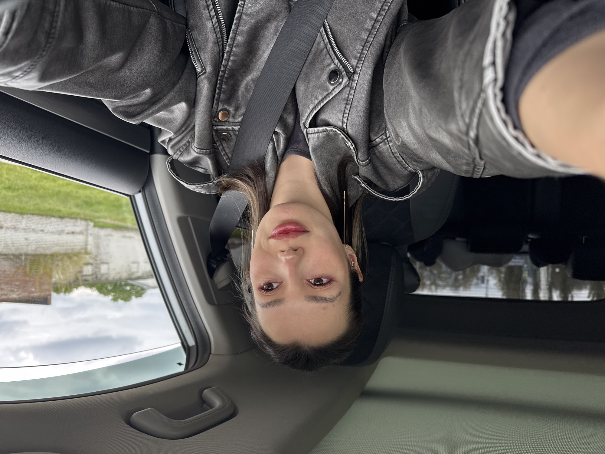 Woman in gray jacket observed in car during urban drive