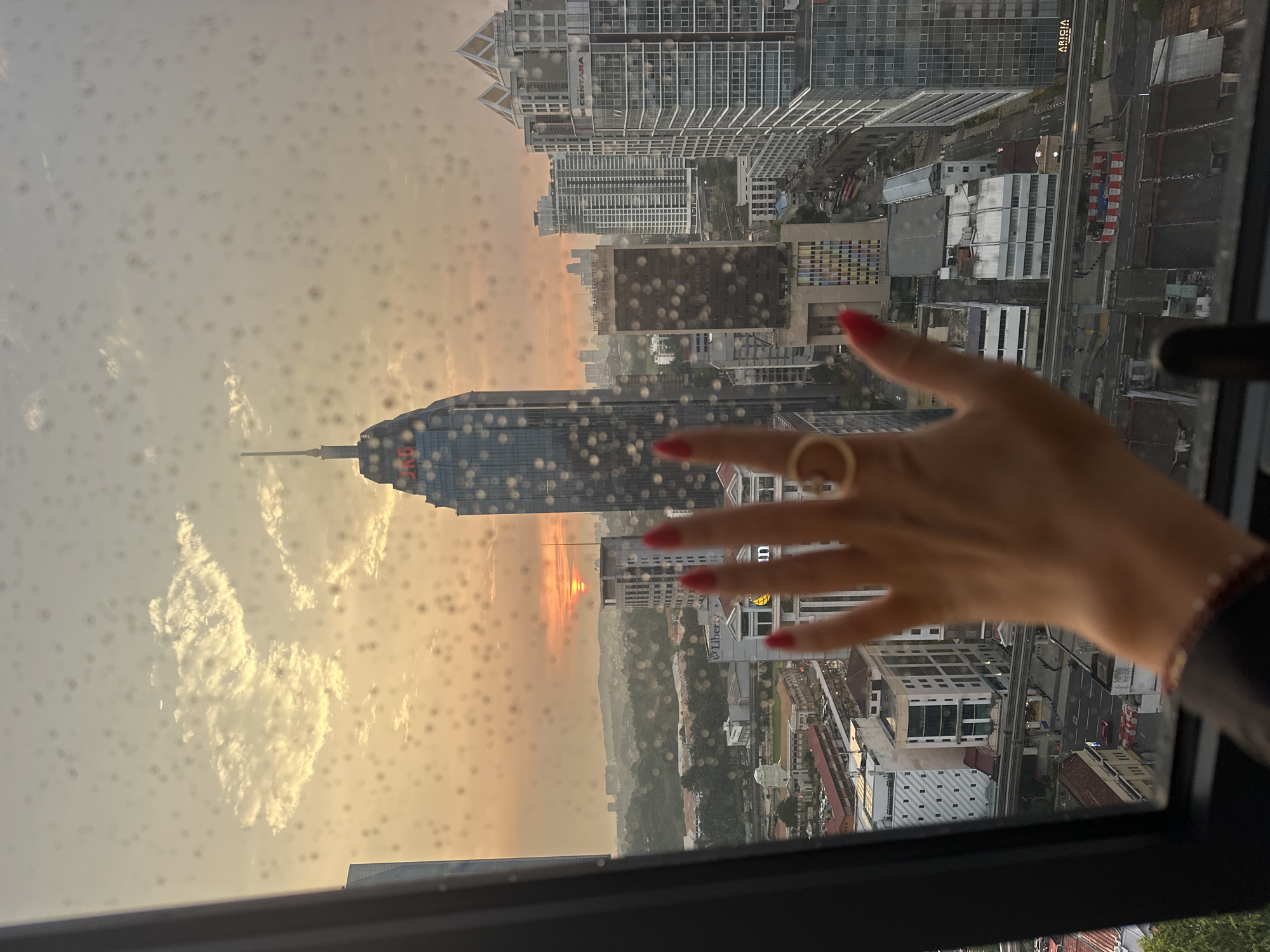 Rainy window view captures Kuala Lumpur cityscape from high-rise