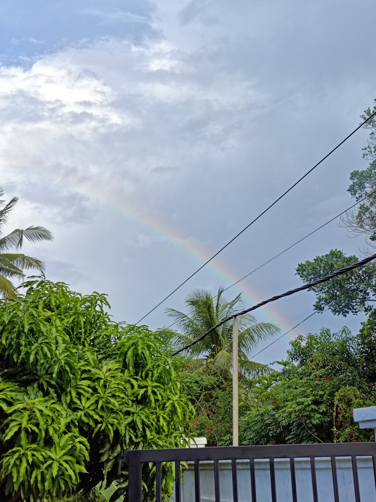 Rainbow appears over cloudy Sumbokrayek amid everyday village activity
