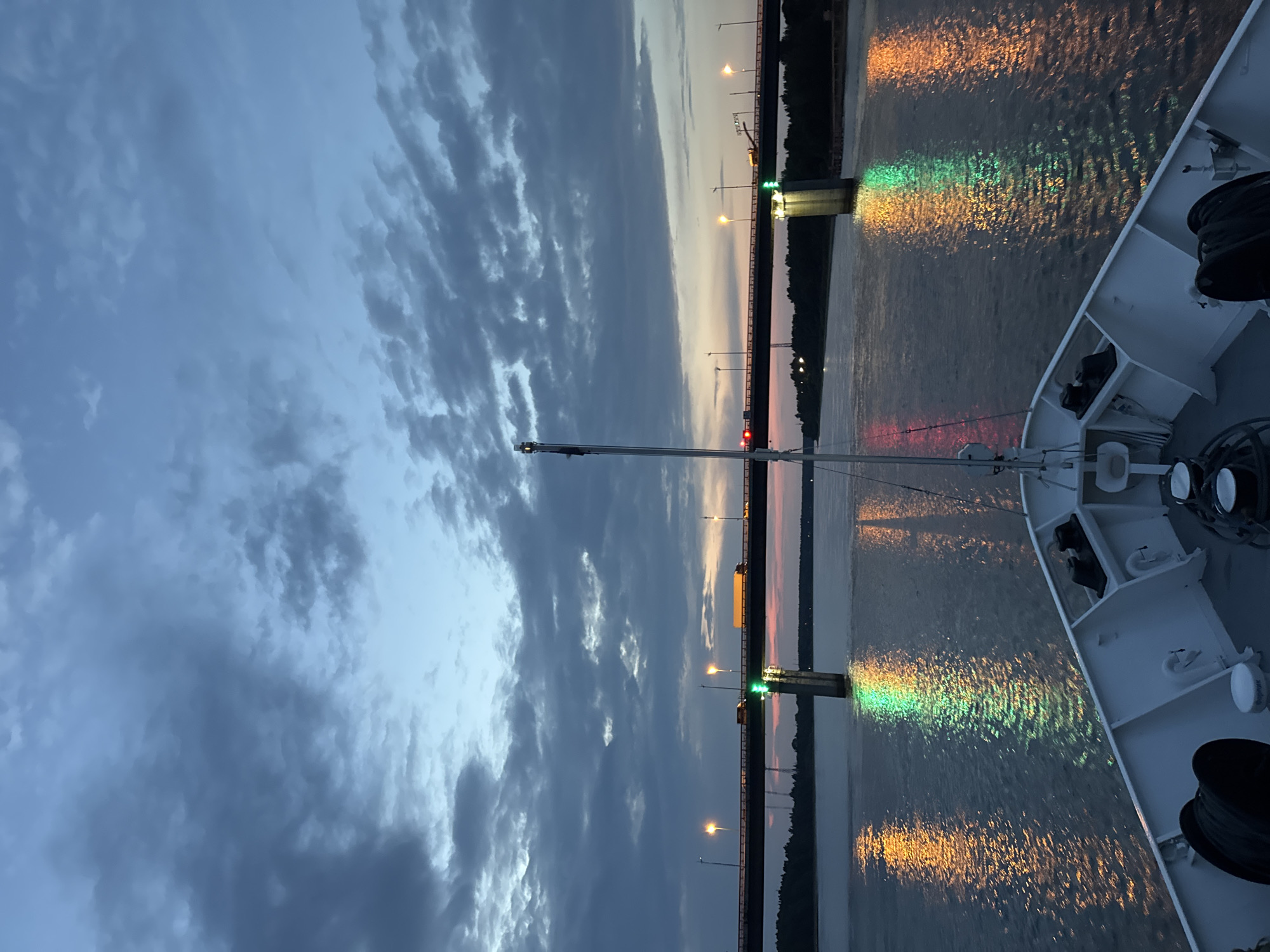 Evening river cruise passing under a lit bridge in Kirovsk