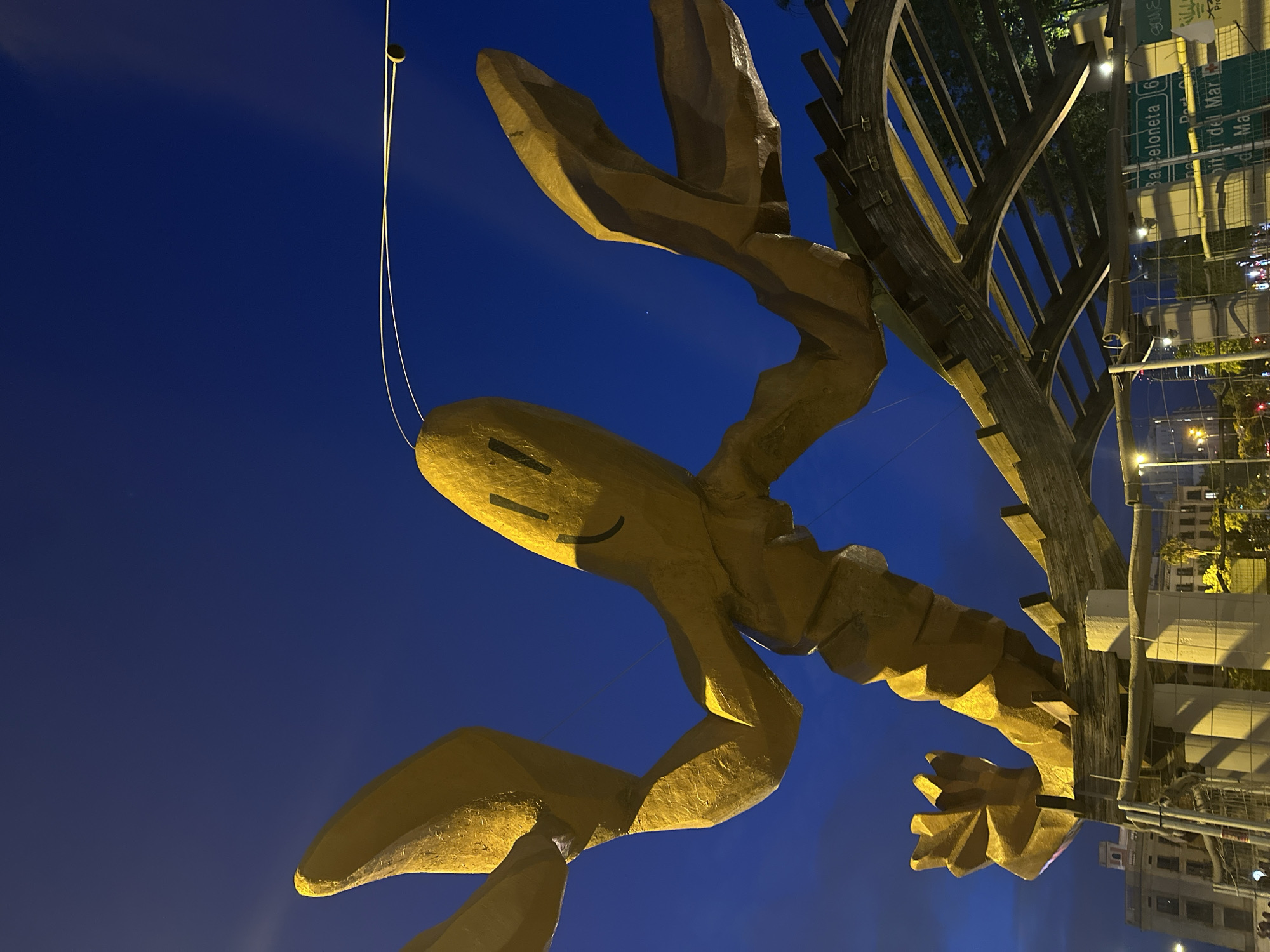 Golden lobster sculpture illuminated at night in Barcelona plaza