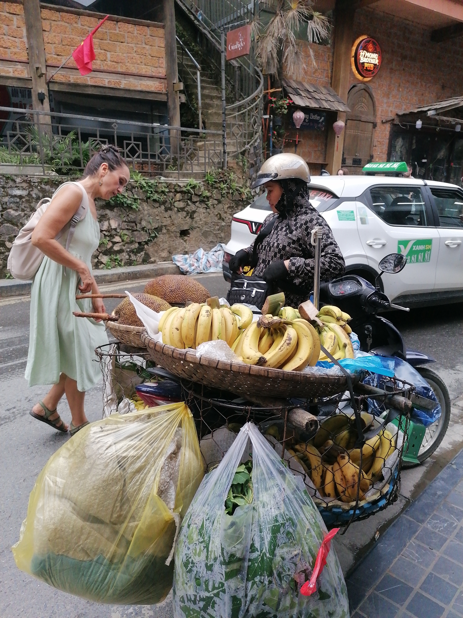 Woman shops at motorcycle fruit cart in Sa Pa Ward
