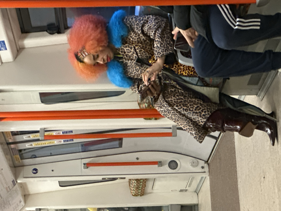 Colorfully dressed passenger rests on London train
