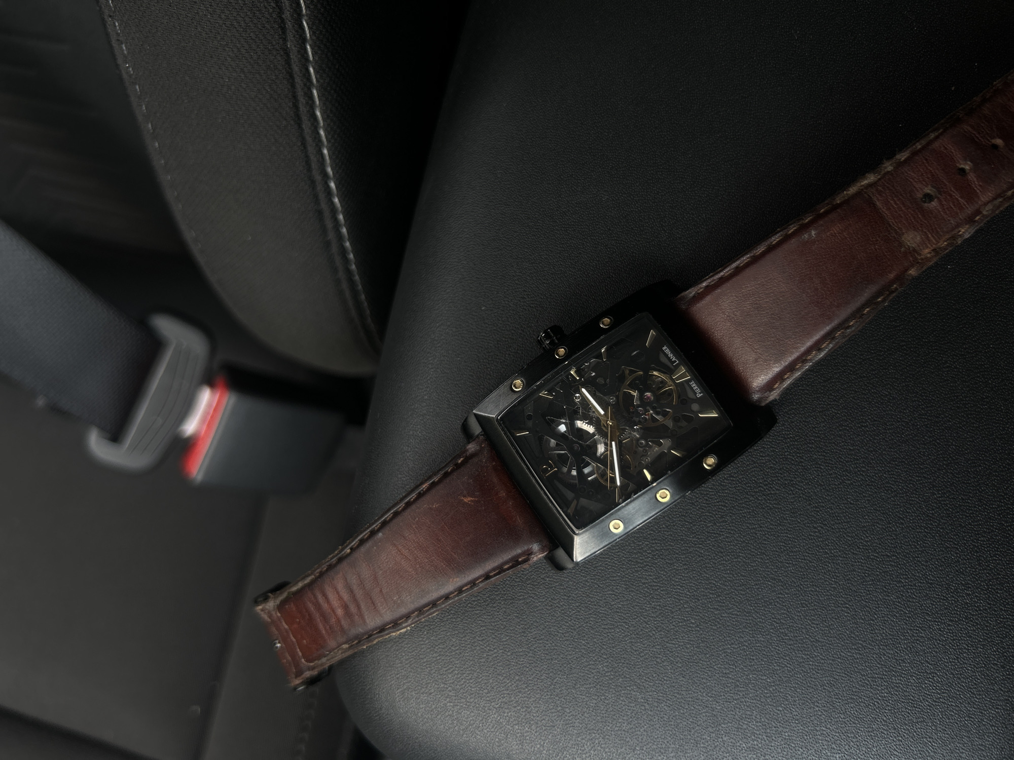 Person examines skeleton watch inside parked vehicle during midday