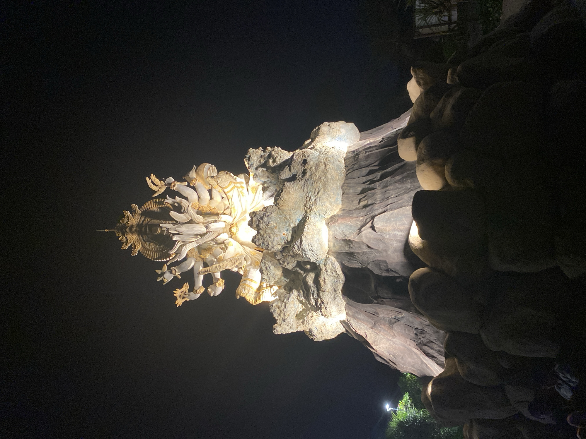 Nighttime visitor captures illuminated Hindu sculptures, lunar halo at Bali park