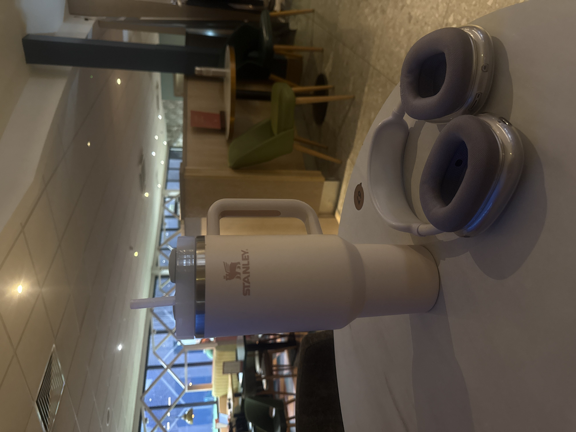 Travel mug and headphones spotted on London coffee shop table