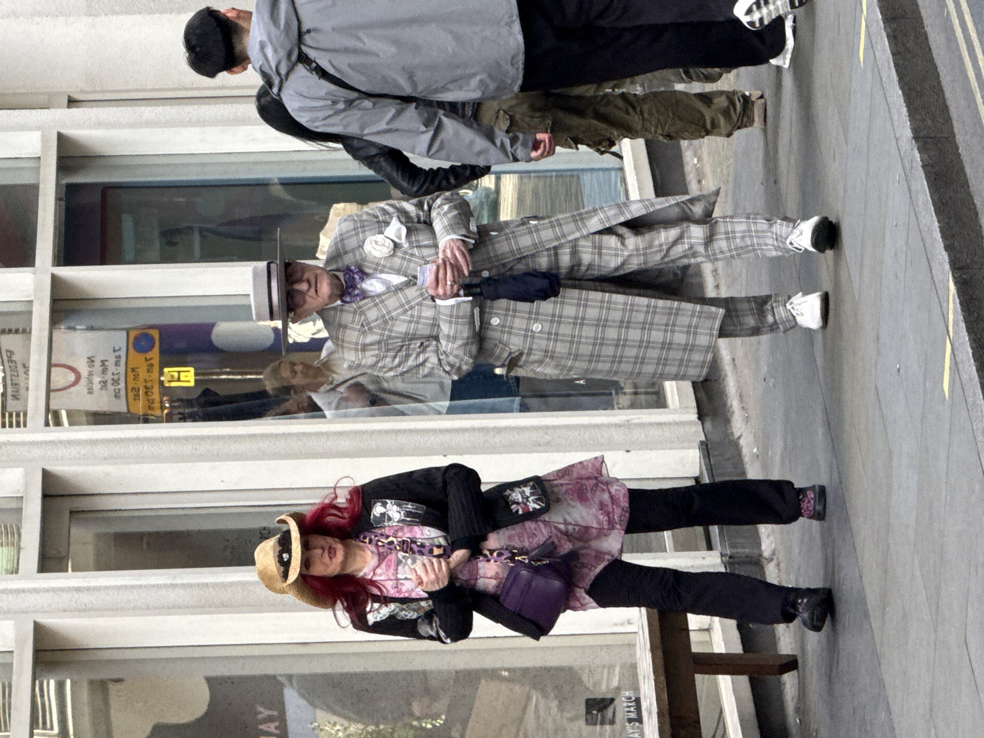 Pedestrians walk London sidewalk, man carries rubbish bags