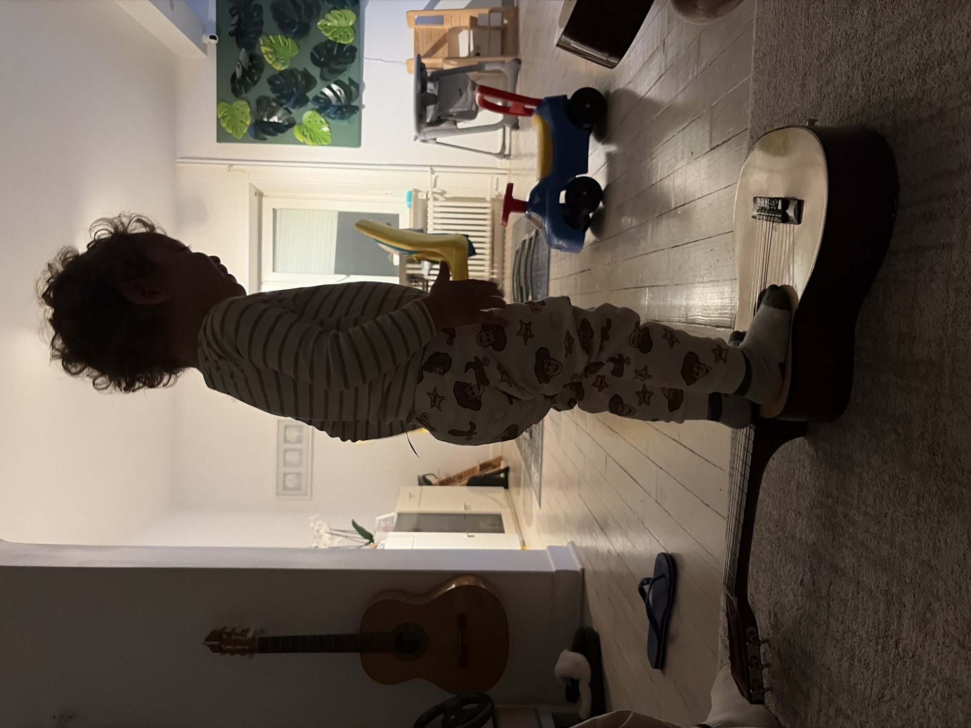 Child plays with guitar in pajamas in Luxembourg home